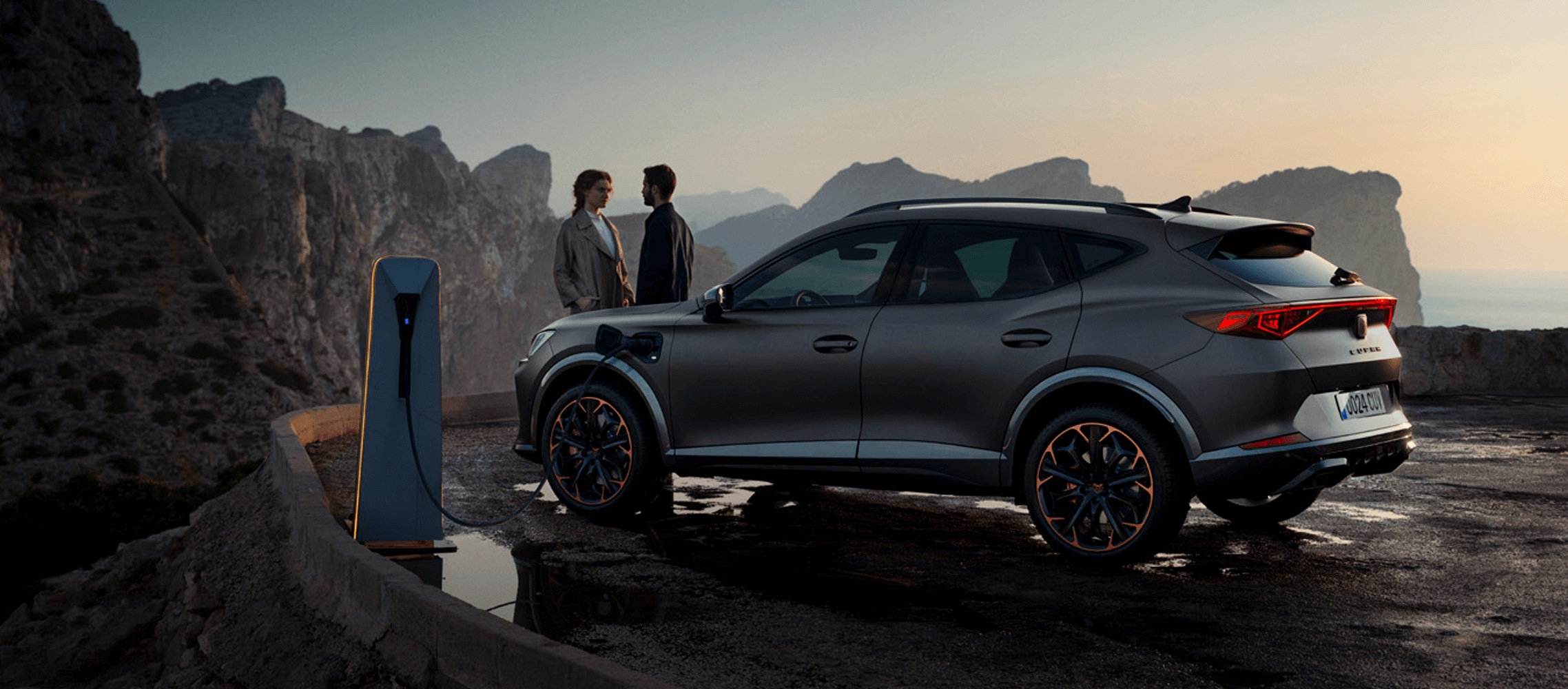 Ludzie stojący obok dużego auta rodzinnego CUPRA Ateca Ludzie stojący obok dużego auta rodzinnego CUPRA Ateca